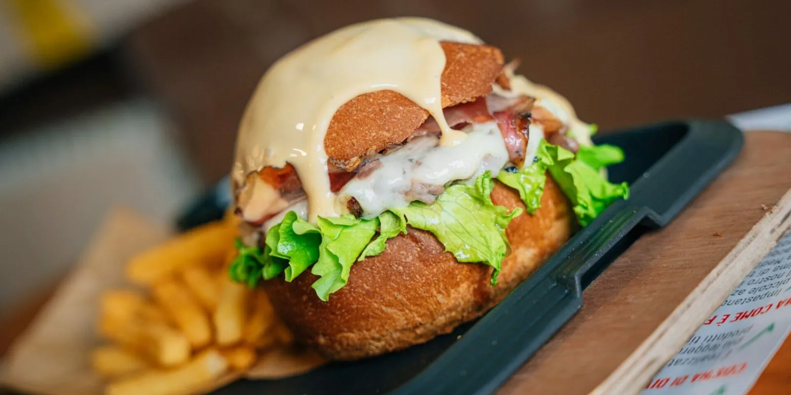 Burger di Black Angus con bacon e formaggio fuso servito al tavolo nella sala della Brasserie