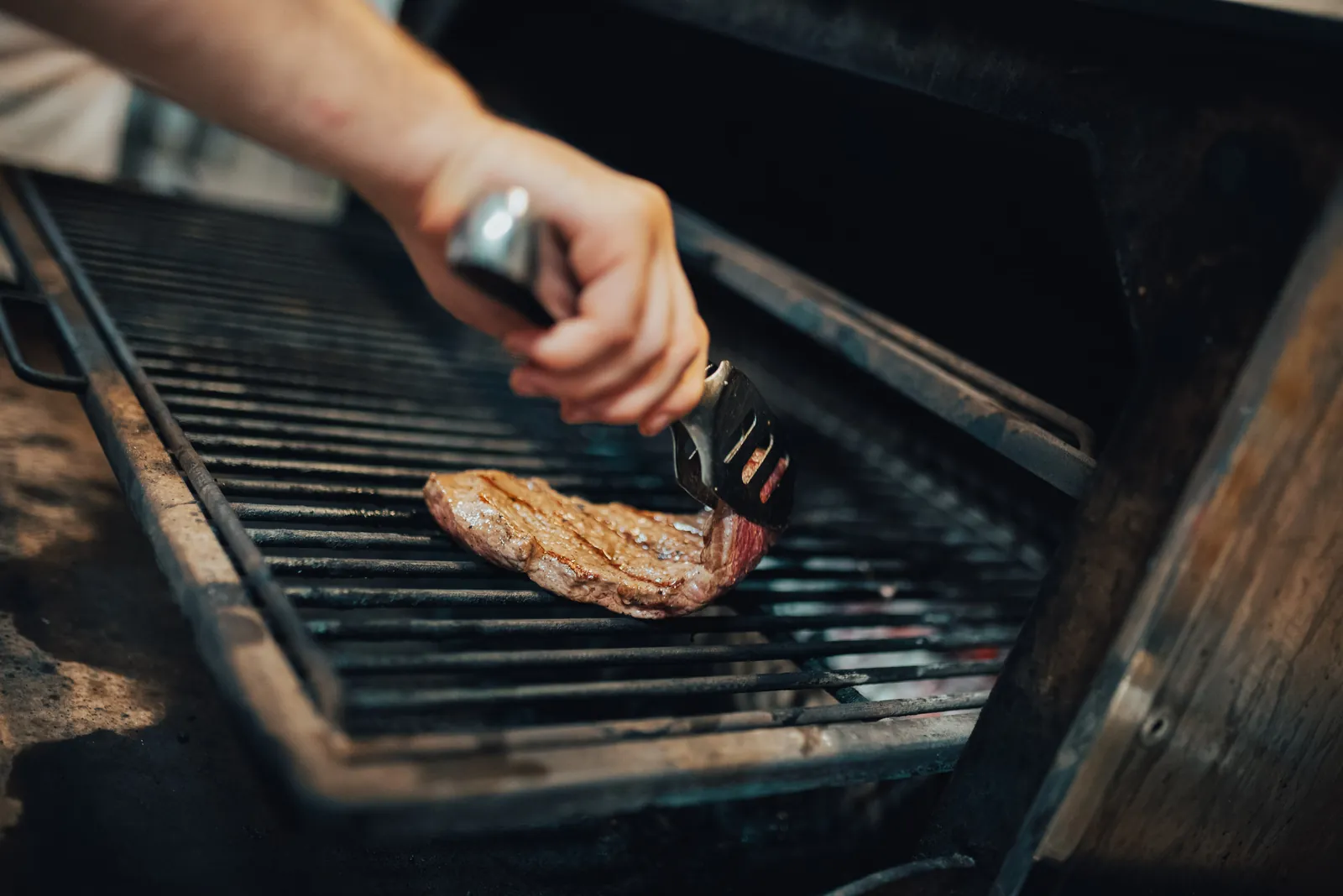 La pinza gira una bistecca sulla griglia rovente del forno Josper della Brasserie