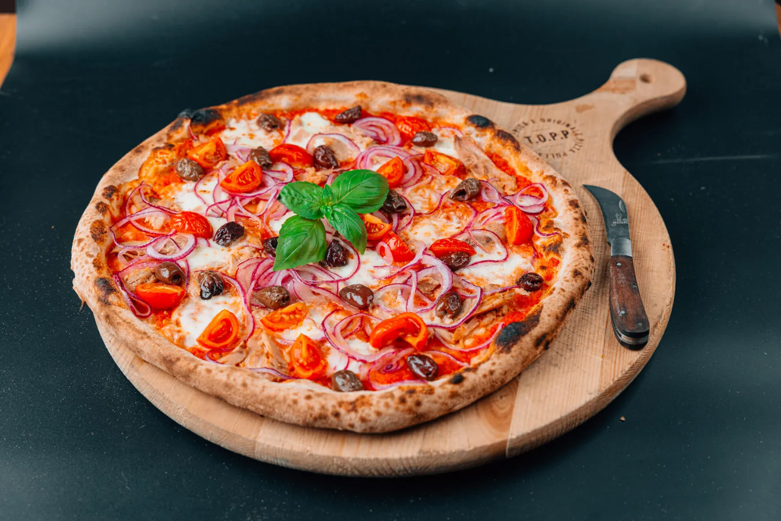 Pizza servita sul tagliere di legno T.O.P.P. con la roncola appoggiata accanto
