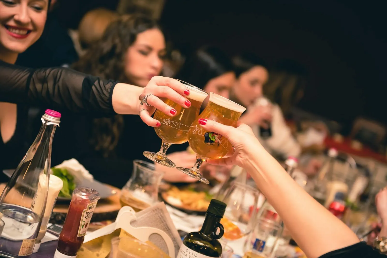 Brindisi con i calici di birra a una tavolata di amici alla Brasserie